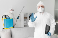 Há dois homens vestidos com equipamentos de proteção. Eles fazem serviços de dedetização.