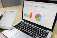 Imagem de um notebook com a tela aberta, na tela, constam gráficos nas cores azul, amarela, vermelha