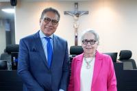 À esquerda, homem alto, moreno, usando paletó azul de gravata azul; à direita, mulher idosa de cabelo grisalho usando roupa blase rosa e camisa branca