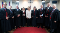 seis homens de toga preta e ao centro três mulheres, sendo duas de toga preta e uma de calça preta e camisa branca