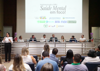 Várias pessoas sentadas em uma formação de mesa.