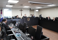 Há uma bancada com computadores com homens e mulheres digitando.