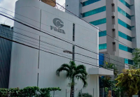 Dois prédios, sendo o da esquerda branco e menor do que o da direita, com o nome TV Gazeta e a logomarca da empresa em letras cinzas escuras; à direita, um edifício maior com janelas de vidros de cor verde.