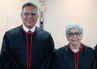 Há duas pessoas vestidas toga preta. Sendo um homem e uma mulher de estatura mediana.