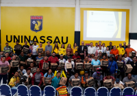 Grupo de pessoas reunidas para uma foto. Há um telão com o fundo amarelo.