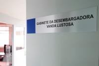 Foto de uma porta cor cinza-claro aberta; nela, há as seguintes palavras: GABINETE DA DESEMBARGADORA VANDA LUSTOSA escritas em letras pretas e todas maiúsculas.