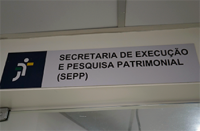 Placa de PCV cinza com as letras pretas escrito Secretaria de Execução e Pesquisa Patrimonial (SEPP)