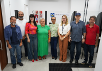 Há quatro homens e quatro mulheres. Eles estão de pés reunidos para uma foto.