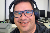Homem branco de óculos preto usando o handfone preto