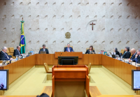 auditório com bancadas de madeira e homens de terno sentados por trás das bancadas