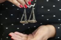 Mão de uma mulher com unhas vermelhas segurando uma balança