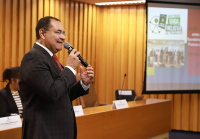 Homem pardo de terno escuro com um microfone na mão