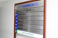 Placa de sinalização no 7º pavimento da 7ª Vara indica, com setas para a esquerda: Sala de Audiência, Gabinete dos Juízes, Banheiros, Secretaria, Gabinete do Diretor e Saída de Emergência.