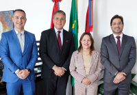 Foto de quatro autoridades em pé pousadas para fotos, sendo três homens altos de terno e uma mulher baixa de terno cáqui 