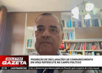 A imagem mostra um homem participando de uma entrevista por vídeo, com estante de livros ao fundo. Na parte inferior, há uma tarja com o título da matéria exibida no telejornal “Boletim Gazeta”: “Proibição de declarações de comparecimento em UPAs repercute no campo político”.