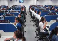 Foto com vários operadores de telemarketing, homens e mulheres, sentados trabalhando.