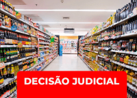 Imagem de um corredor de supermercado, com prateleiras cheias de produtos dos dois lados. Em destaque, na parte inferior da imagem, há uma faixa vermelha com o texto em branco: “DECISÃO JUDICIAL”.