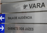 Placa indicativa na cor prata, con letras na cor preta. Há escrito nela, 9ª Vara, logo abaixo há, grafado salda de audiência e gabinetes dos juízes.