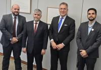 Quatro homens, sendo dois brancos e dois pardos, em pé e de terno escuro