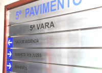 A imagem mostra uma placa de sinalização interna de um prédio. Nela está escrito em destaque “5º PAVIMENTO” e “5ª VARA”. Há também setas indicando direções para “SALA DE AUDIÊNCIA” e “GABINETE DOS JUÍZES”.