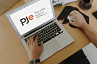 A imagem apresenta um computador com duas mãos digitando na tela a palavra PJe