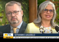 A imagem mostra uma reportagem de TV sobre o Setembro Amarelo, com um homem de terno e uma mulher de blazer camarelo dando entrevista. Na tarja, aparece a mensagem de que o TRT/AL vai promover ações de apoio à saúde mental.