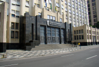  Fachada de um prédio grande e imponente de estilo art déco, que abriga o Tribunal Regional do Trabalho. A estrutura é feita de granito escuro na parte central e as paredes são de cor bege. O calçamento em frente ao prédio tem um padrão em preto e branco. Acima da entrada, lê-se a inscrição "JUSTIÇA DO TRABALHO - TRIBUNAL REGIONAL DO TRABALHO".