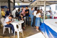Imagem da várias pessoas em pé ao lado de diversas barracas de feira