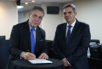 Dois homens pardos de ternos escuros assinando um papel