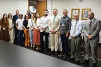 Treze pessoas em pé posadas para a foto, sendo oito homens e cinco mulheres. Todos estão bem vestidos, com roupas formais