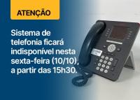 Telefone tradicional preto de teclas brancas ao lado direito; ao lado esquerdo, a frase Sistema de telefonia ficará indisponível nesta sexta-feira a partir das 15h30 escrita em letras brancas