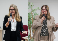 Há duas mulheres falando ao microfone, lado a lado, em momentos diferentes. À esquerda, uma mulher de cabelos loiros e lisos, usando óculos e um conjunto social preto com camisa branca. À direita, outra mulher de cabelos castanhos e lisos, também com óculos, veste um terno bege e blusa estampada em preto e branco,