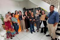 Grupo de pessoas posando para foto. Eles estão sorridentes e seguram um cordão estilizado.