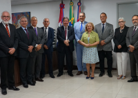 Oito homens e duas mulheres em frente das bandeiras do Brasil e de Alagoas