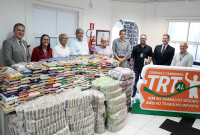 Várias pessoas reunidas em volta de um pilha de sacos de alimentos.