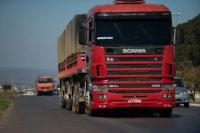 Foto de uma rodovia e, em destaque, uma carreta Scania de cor vermelha