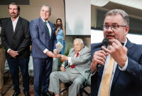 A imagem está dividida em duas partes. À esquerda, três homens aparecem em um ambiente formal. O homem ao centro, de terno azul, está entregando um troféu ou placa de homenagem a um senhor idoso, que está sentado em uma cadeira de rodas e veste terno cinza com gravata vermelha. À esquerda deles, outro homem, de terno escuro e camisa clara, observa a cena. Ao fundo, uma mulher segura um microfone e parece conduzir o evento. À direita da imagem, um homem de terno escuro.