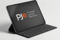 Foto de um notebook preto com o nome Pje ao centro