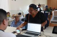 Mulher negra sendo atendida por um homem em frente a um computadot