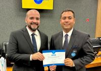 DOIS HOMENS DE TERNO ESCURO SEGURANDO UM CERTIFICADO