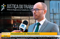Homem calvo, de paletó cinza, concedendo entrista em pé.