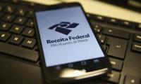Foto de um telefone celular com a tela branca e o nome Receita Federal sobre um teclado preto