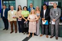 Há homens e mulheres posando para uma foto. Eles estão de pé.