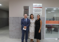 Há três pessoas, sendo um homem de paletó e duas mulheres trajando vestidos.