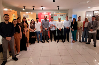 Grupo de homens e mulheres em pé em frente a telas