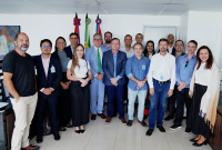 Grupo de homens e mulheres em frente às bandeiras do Brasil e de Alagoas