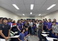 Foto de vários jovens aprendizes em pé posados para a foto; ao centro deles, um home usando blazer creme.