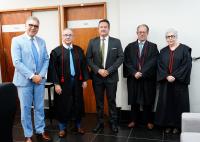 Foto de cinco pessoas em pé, sendo quatro homens e uma mulher idosa. Todos vestem roupas formais