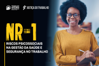 Arte institucional da Justiça do Trabalho sobre a NR-1 e os riscos psicossociais no ambiente laboral. A imagem traz, à direita, uma mulher sorridente segurando uma prancheta, enquanto, à esquerda, aparecem os logos do Programa Trabalho Seguro e da Justiça do Trabalho, além do destaque para o tema “Riscos Psicossociais na Gestão da Saúde e Segurança no Trabalho”.