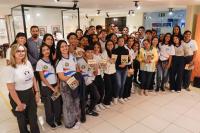 Há um grupo de vários alunos com livros ma mão e dois adultos